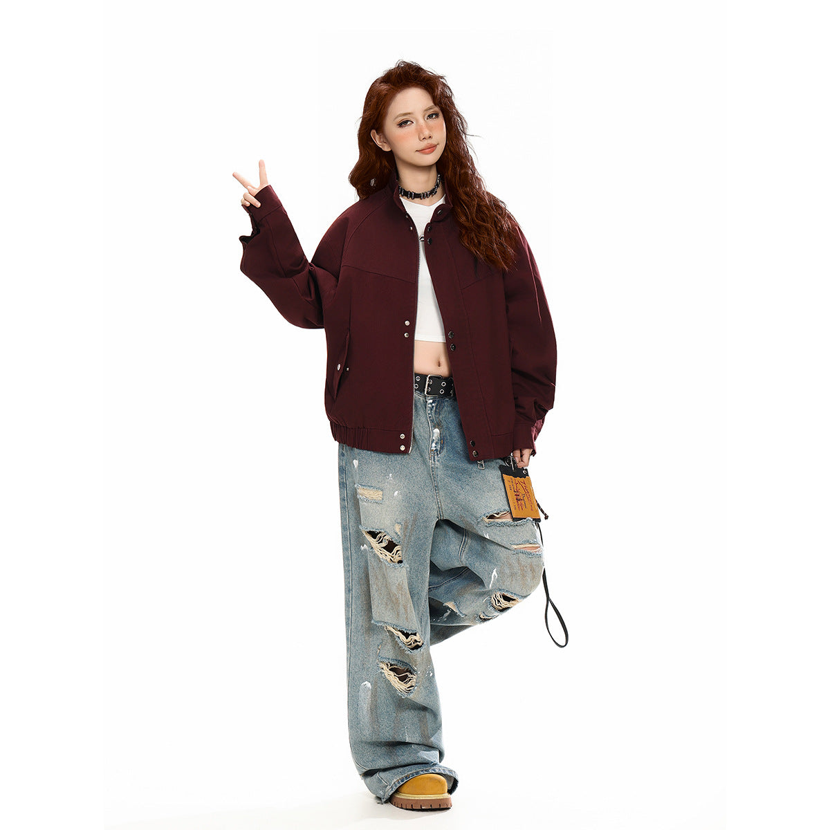 Model wearing a burgundy snap-front jacket with oversized sleeves, a white crop top, and distressed light-wash jeans.