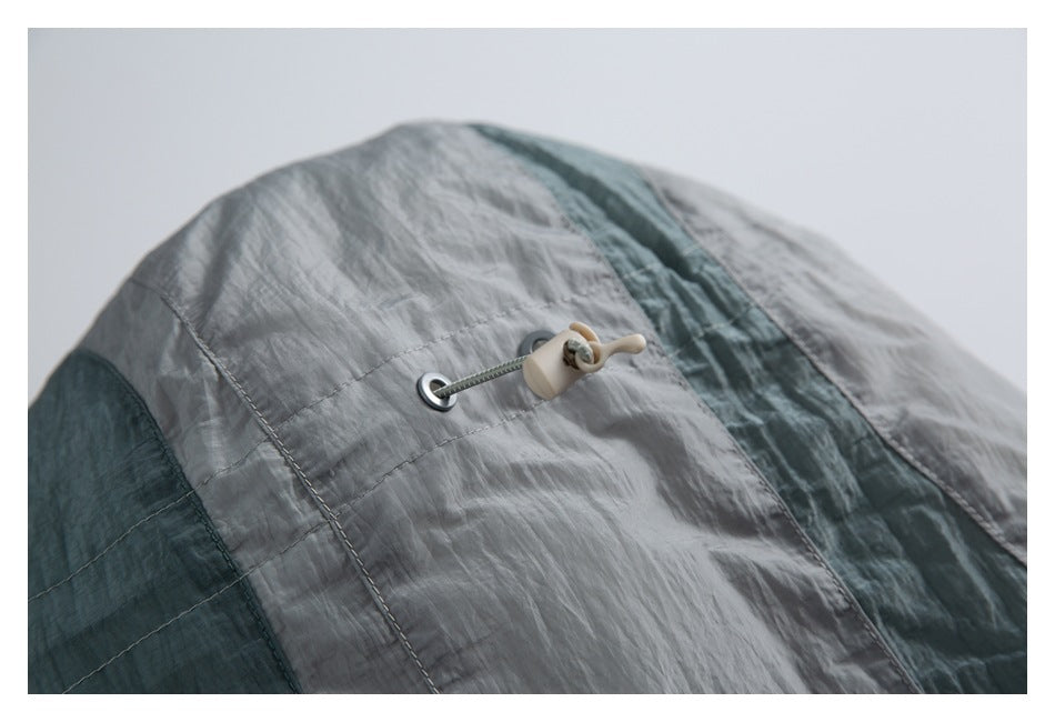 Close-up of a gray and teal garment with a cord, metal eyelet, and toggle fastener.