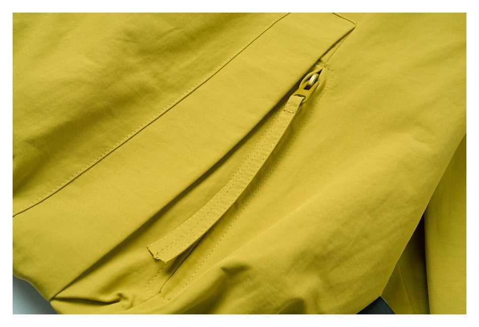 Close-up of a yellow-green garment's flap-covered zip pocket and stitching.