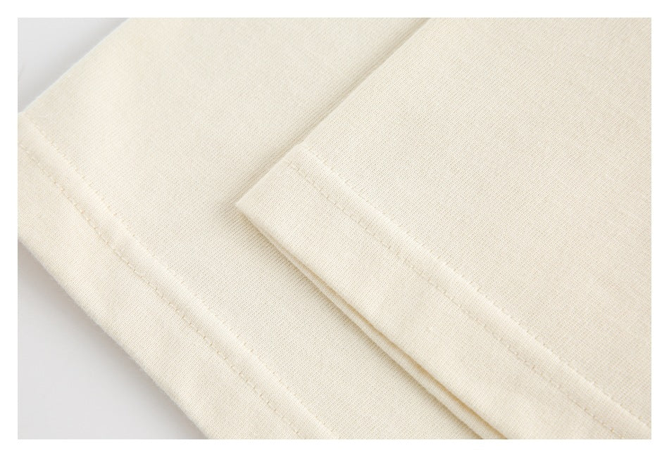 Close-up of cream garment fabric showing folded edges and stitching.
