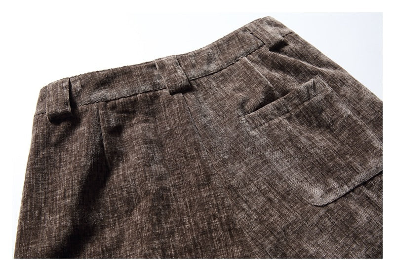 Close-up of the waistband and patch pocket on brown crosshatched trousers.