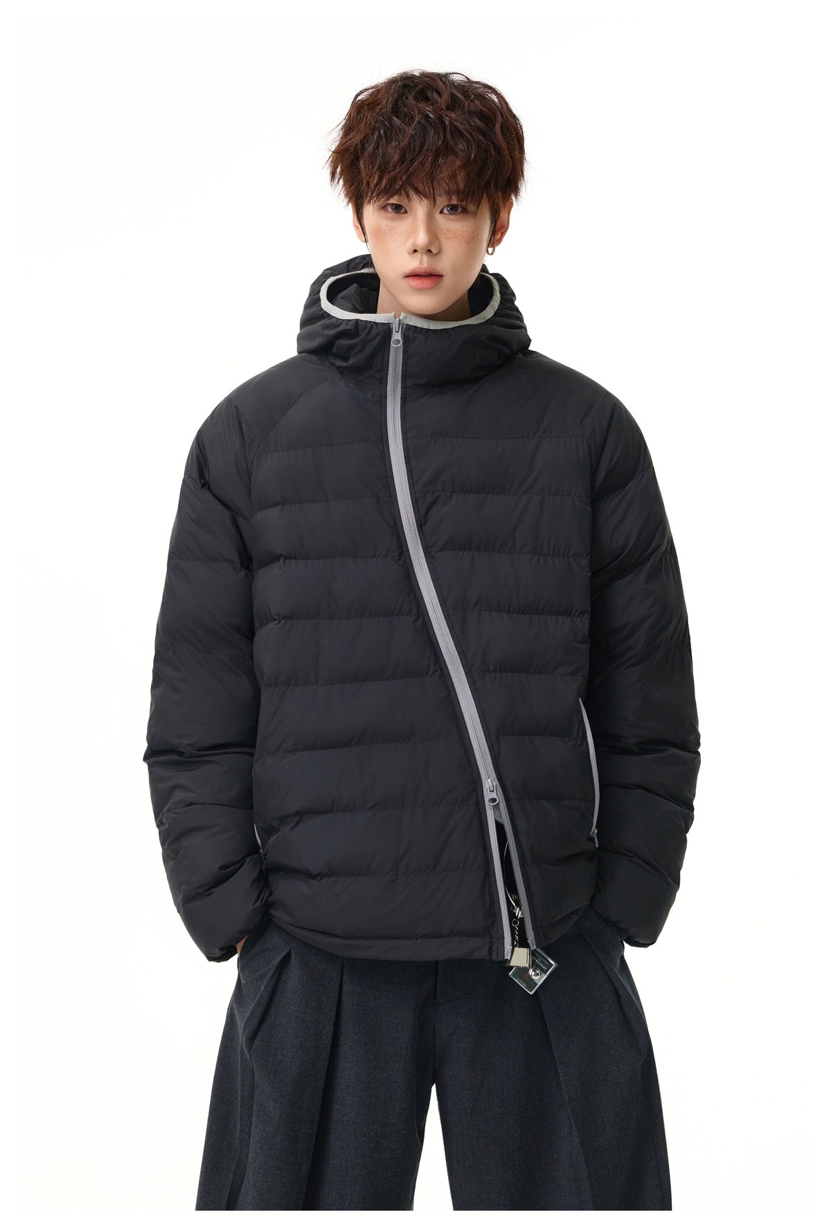 Front view of a model in a black quilted puffer jacket with a hood, light gray trim, and an angled zipper.