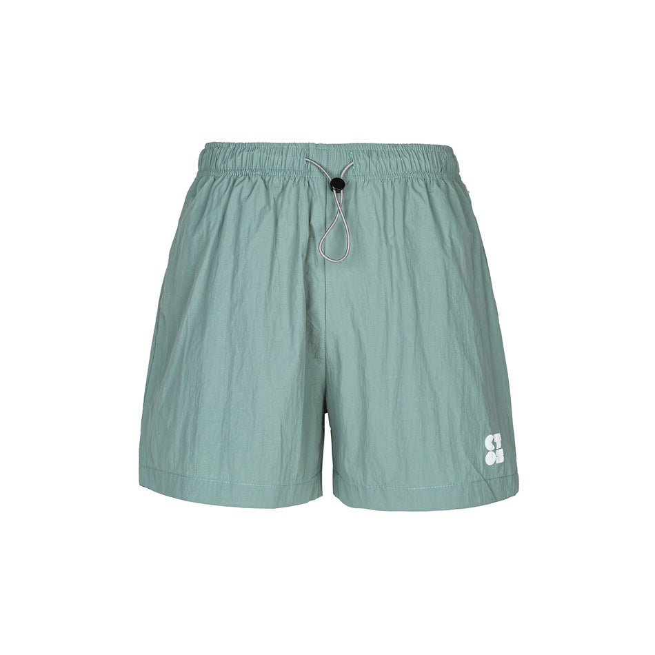 Green crinkled shorts with elastic waist, drawcord toggle and small white print on the lower left leg, front view