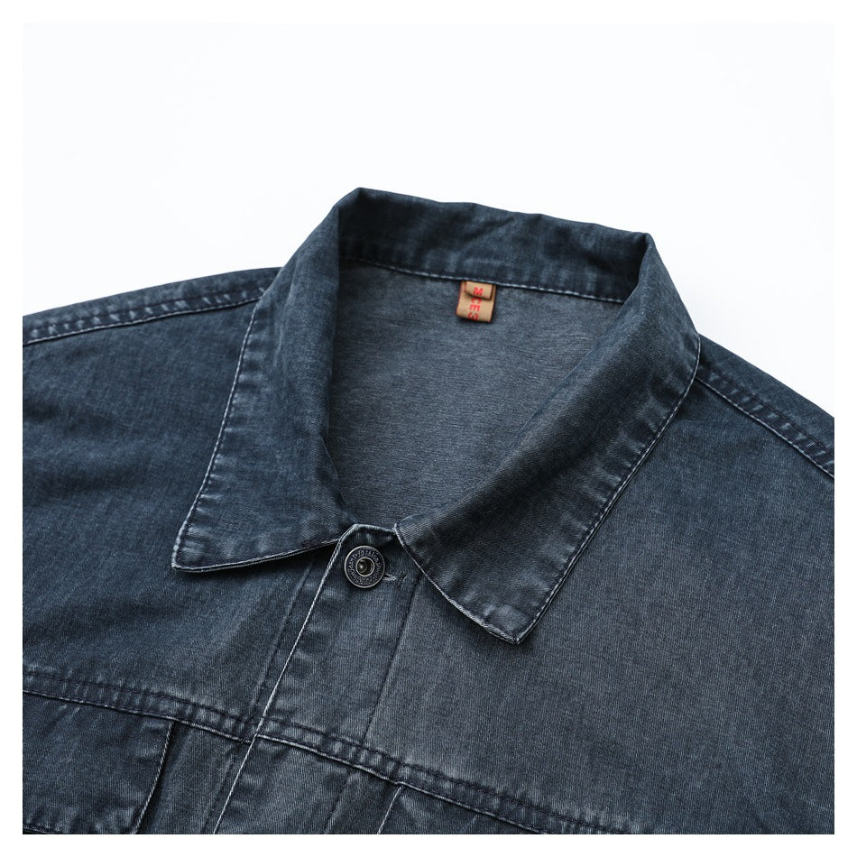 Close-up of a dark blue denim jacket collar, top button, and chest seam.
