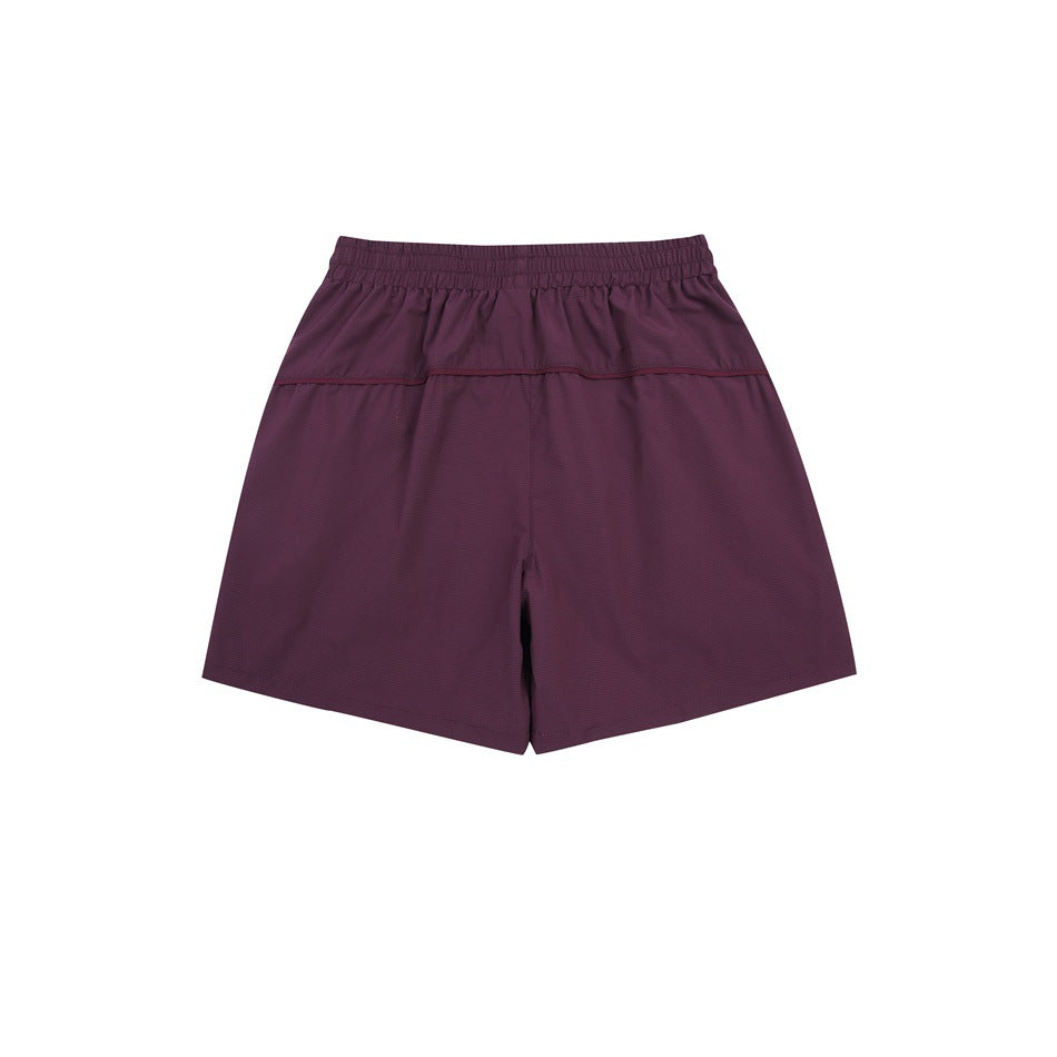 Back view of burgundy athletic shorts with an elastic waistband and horizontal rear seam.