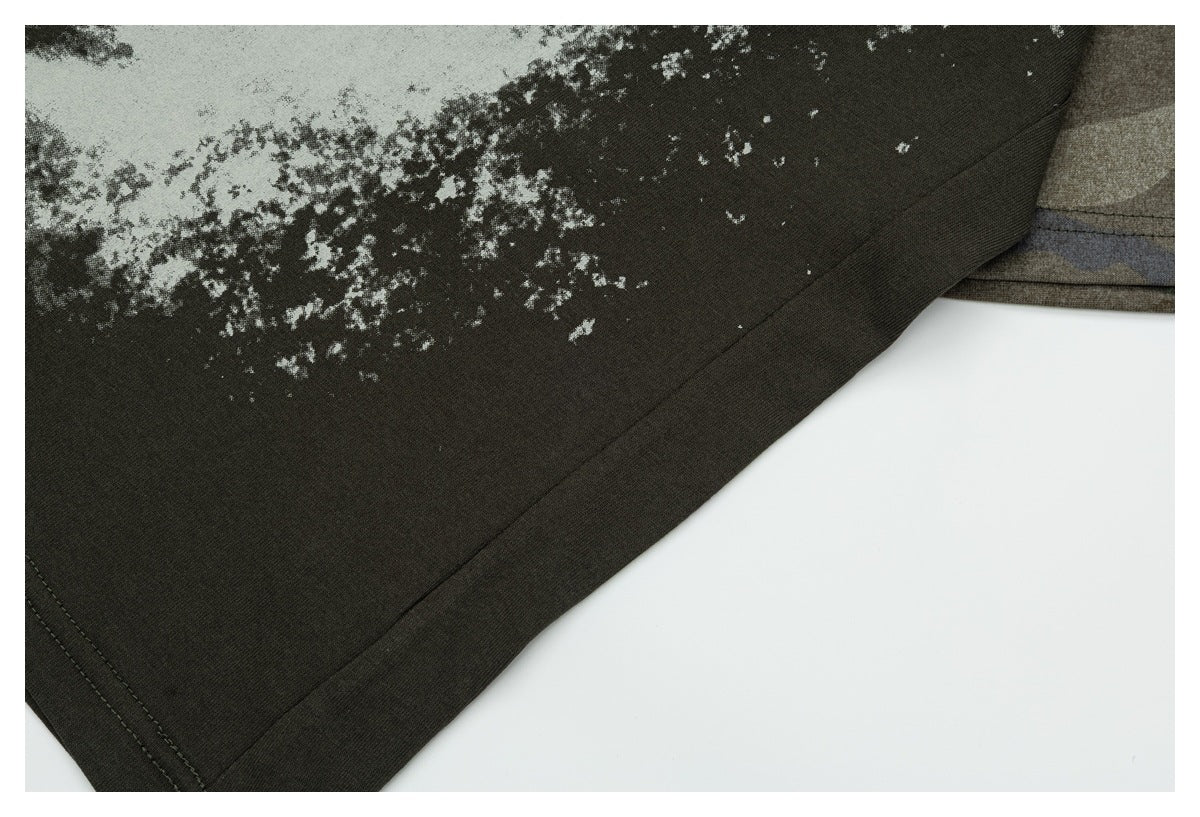 Close-up of the dark olive shirt's lower hem and stitching, with part of its distressed white print visible.