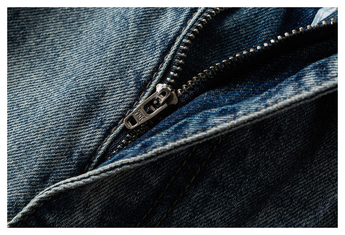 Close-up of a metal zipper and stitching on dark blue denim.