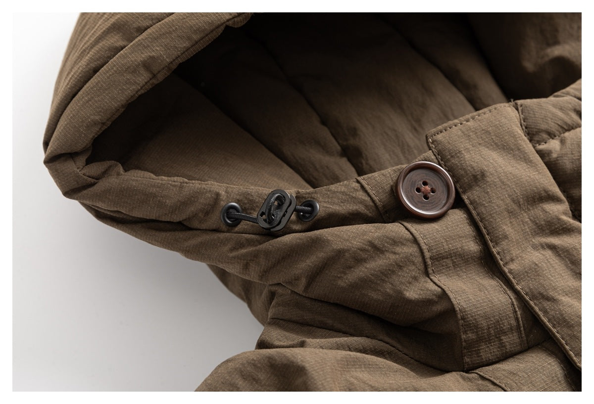 Close-up of a brown hooded jacket showing the hood drawcord toggle and a large brown button.