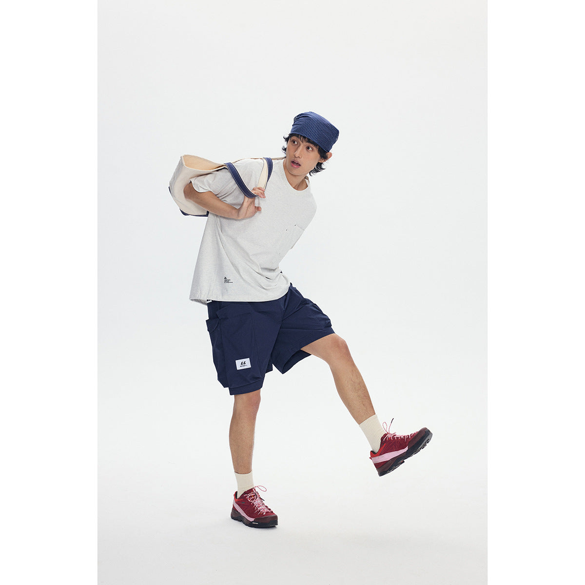 Model wearing an oversized light gray pocket T-shirt, navy cargo shorts, and a navy patterned headscarf.