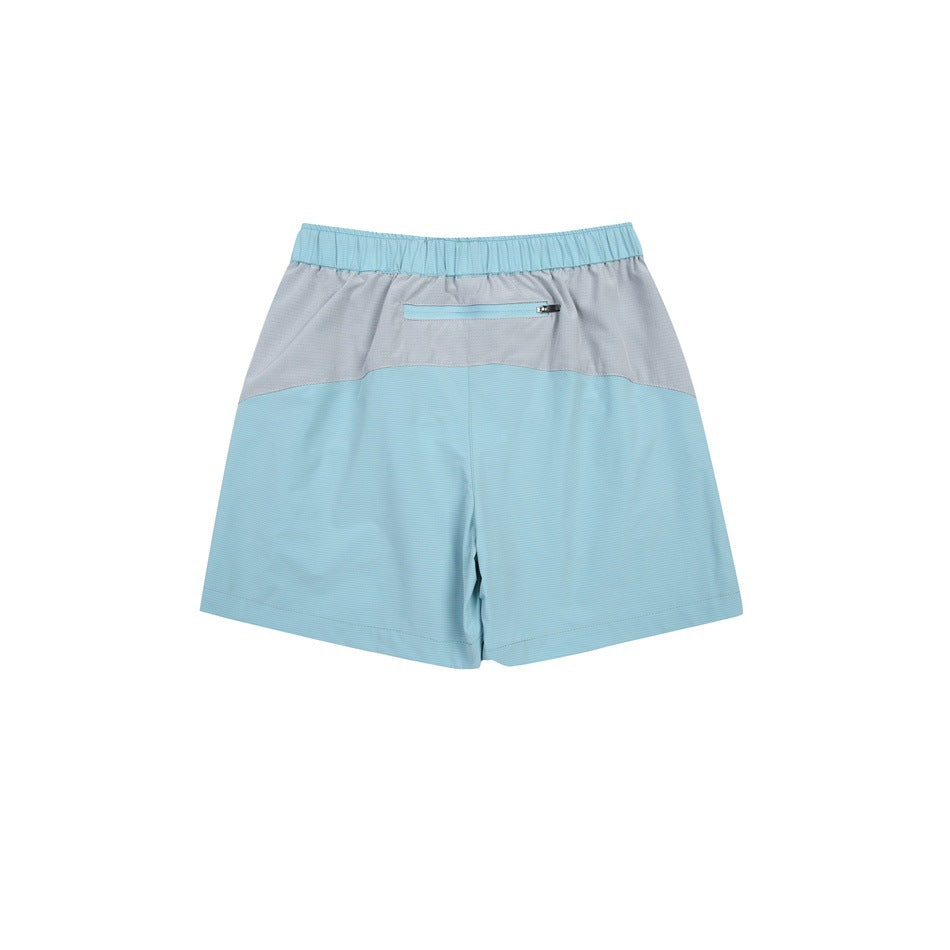 Rear view of a light blue athletic skort with a gray upper panel and a horizontal zippered back pocket.