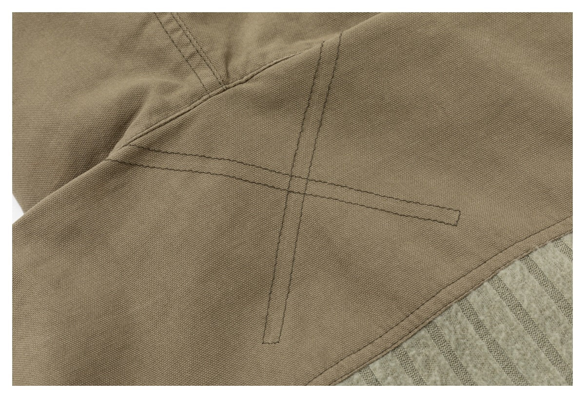 Close-up of a brown garment panel with intersecting stitched seams beside beige striped fabric.