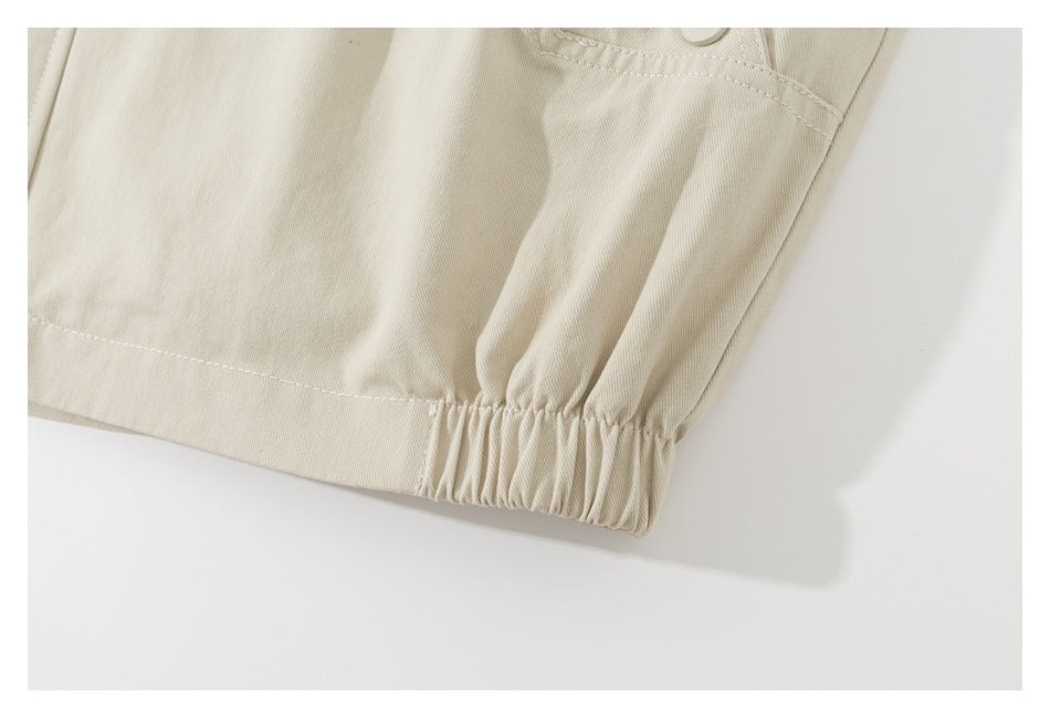Close-up of the beige jacket's hem with gathered elastic at the side.