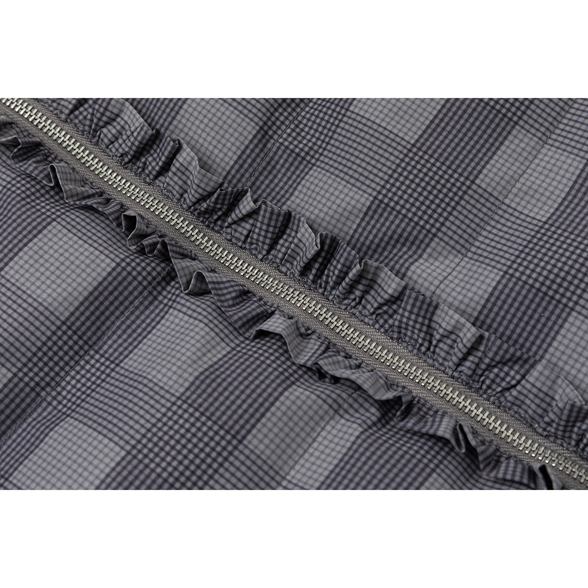 Diagonal metal zipper with ruffled trim on gray-and-black plaid jacket fabric.