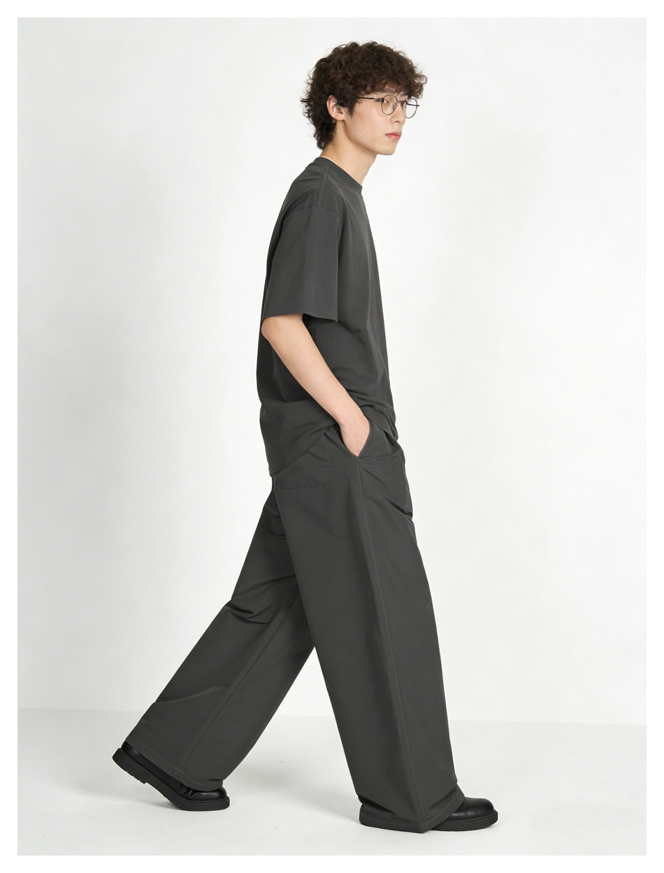 Side view of a model walking in a charcoal oversized T-shirt and matching wide-leg pants.