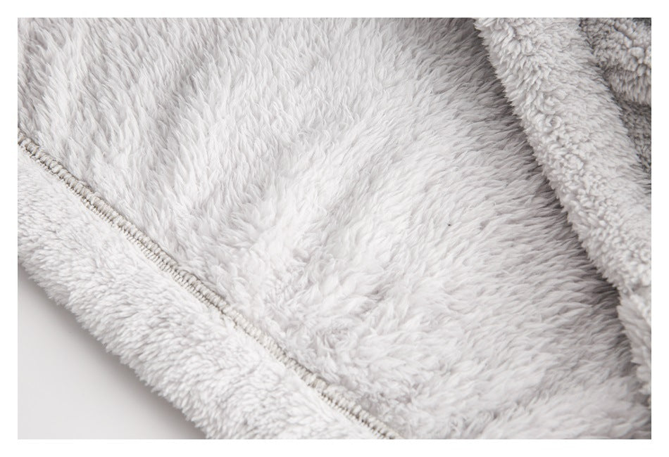 Close-up of pale gray plush fabric and a stitched zipper edge.