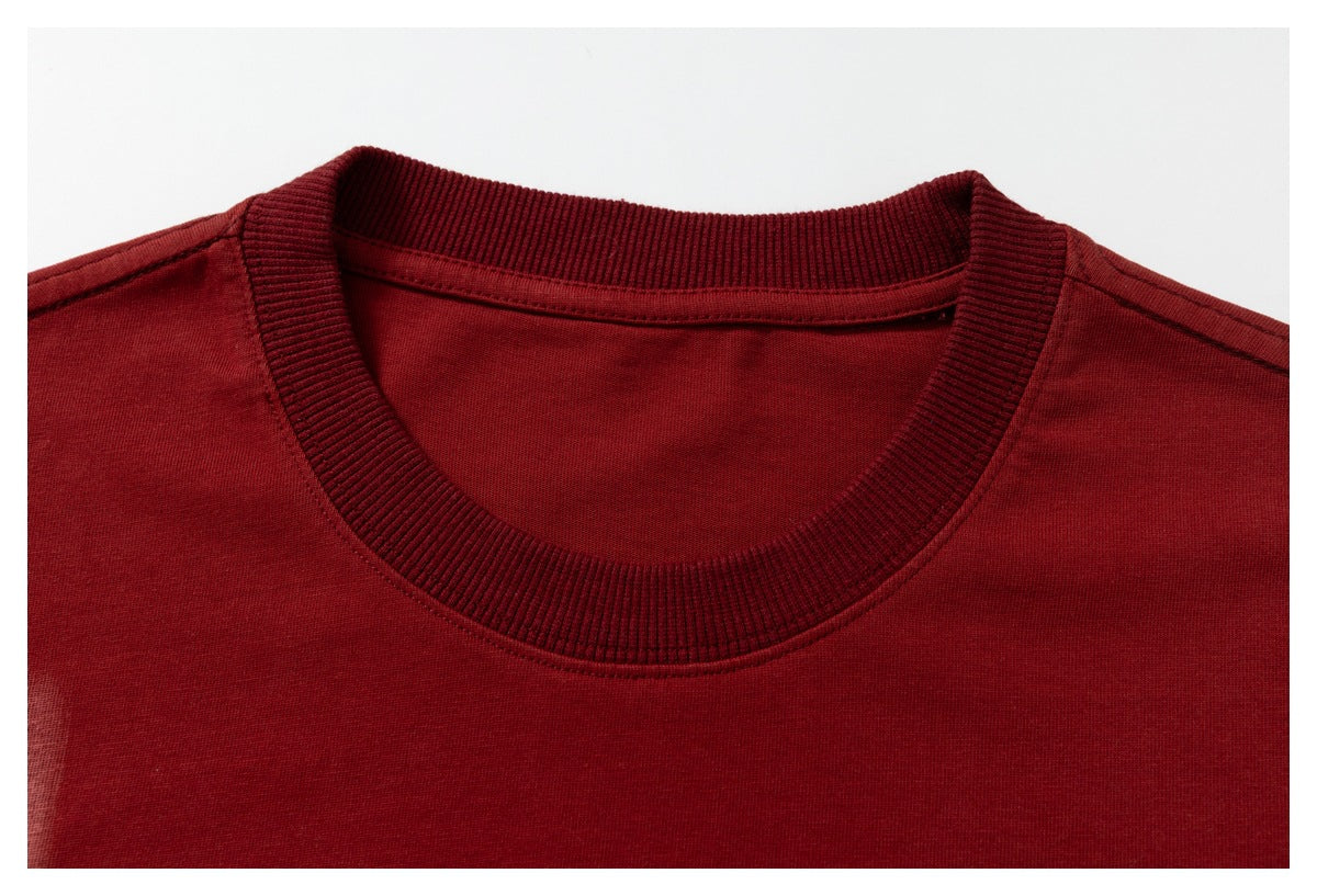 Close-up of a deep red T-shirt's ribbed crew neckline and shoulder seams.