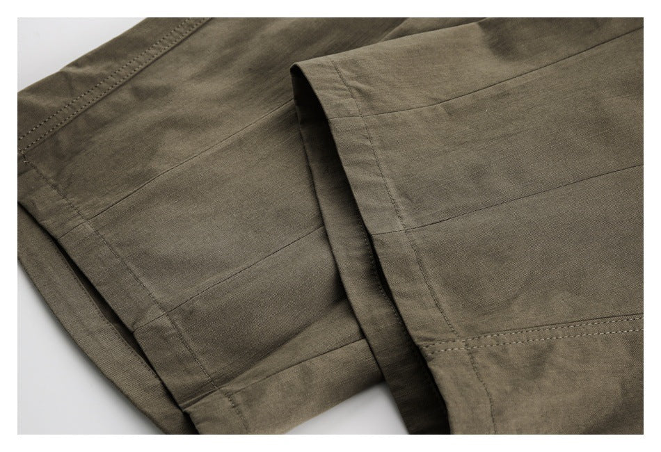 Close-up of olive-brown trouser legs showing stitched panel seams and finished hems.