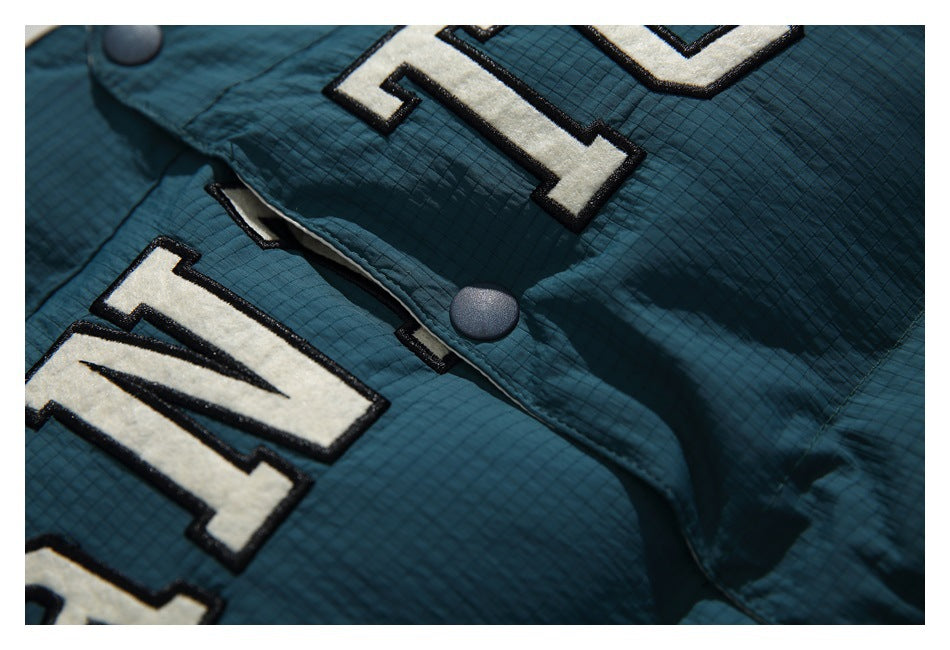 Close-up of a snap on the dark teal vest beside its large cream appliqué lettering.