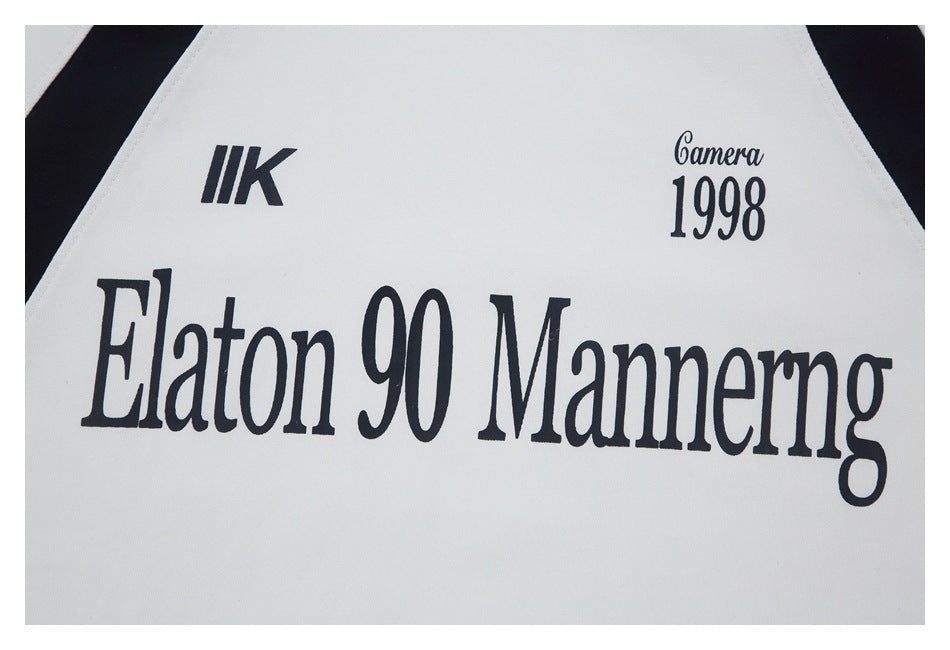 Close-up of black printed lettering and a small “Camera 1998” graphic on white fabric.
