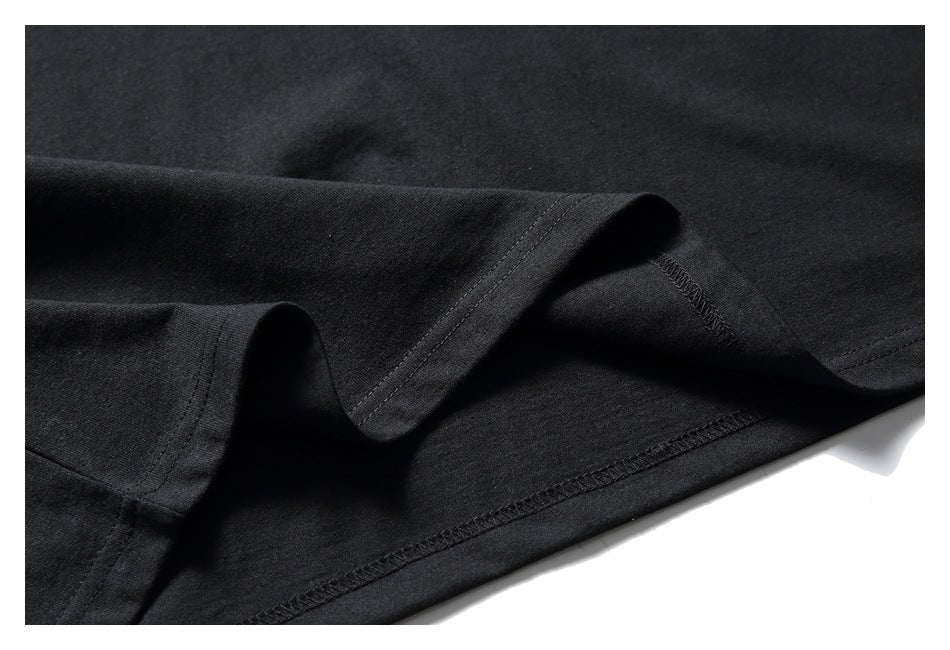 Close-up of the black T-shirt bottom hem, showing the stitched edge and fabric drape.