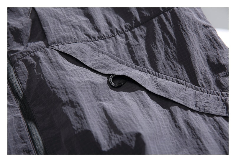 Close-up of a charcoal gray jacket flap and small black ring detail beside a zipper.
