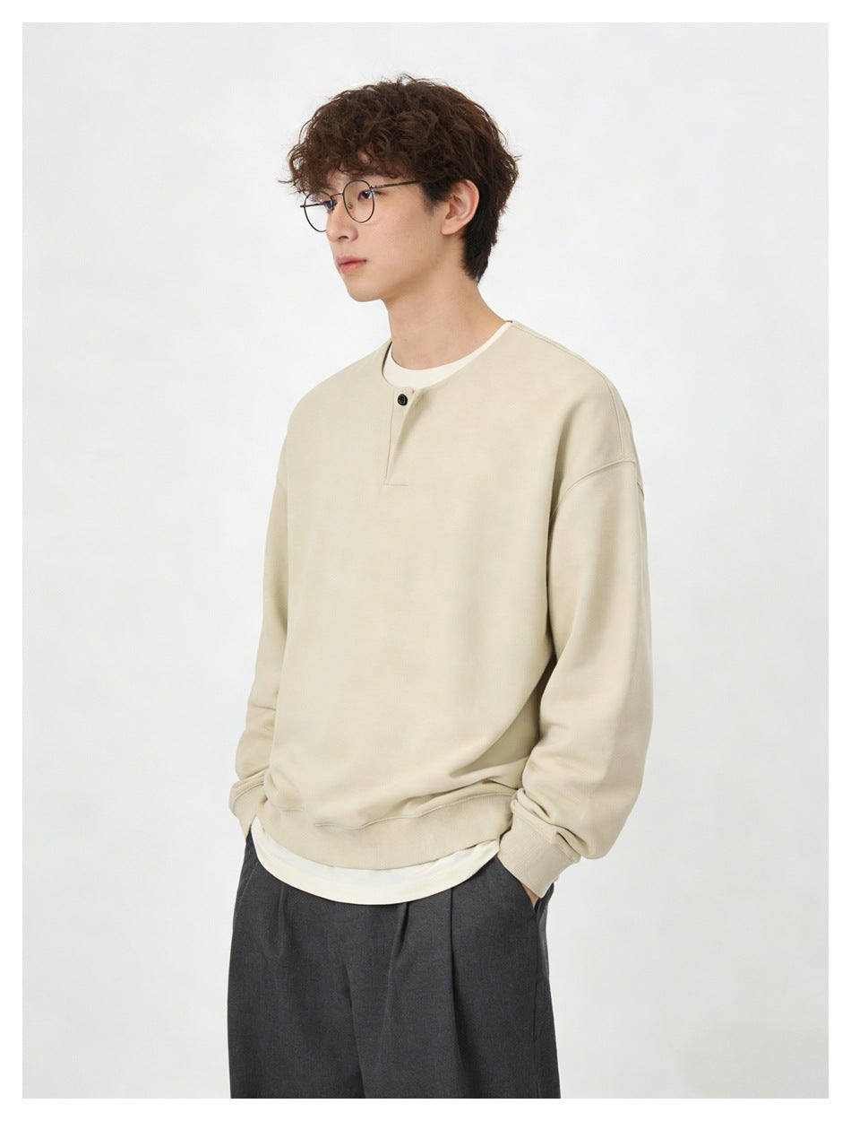 Model wearing an oversized cream sweatshirt with a single-button placket, shown at an angle.