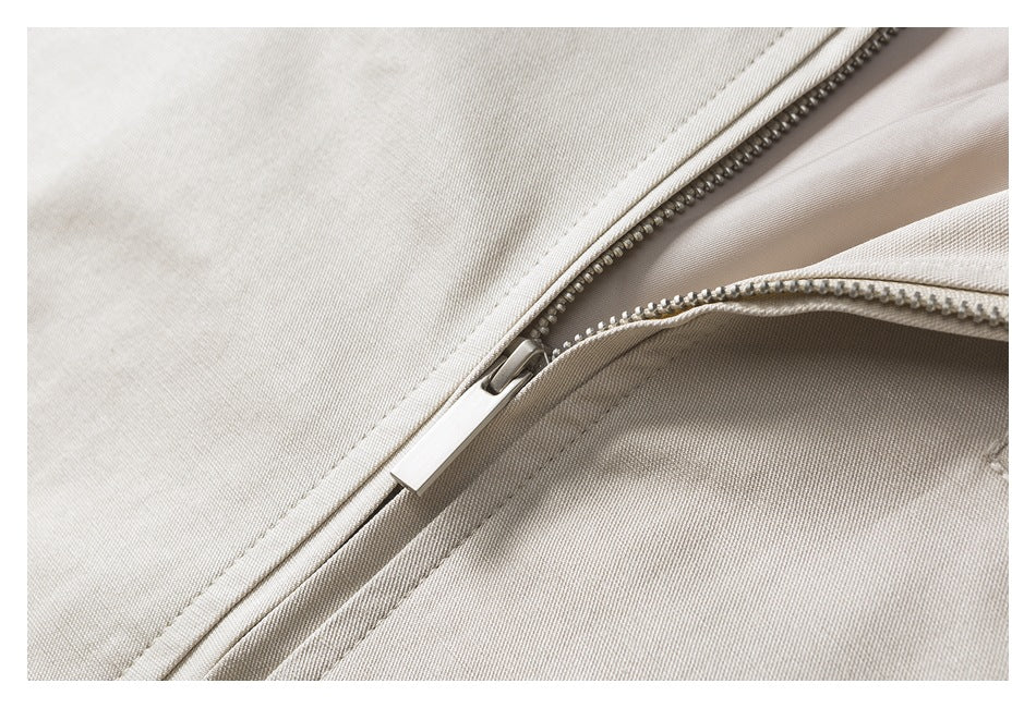 Close-up of a light beige garment with a partially open zipper and visible teeth.