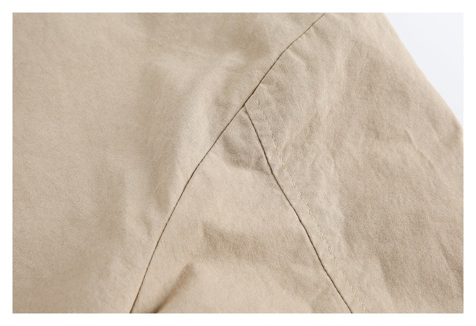 Close-up of beige garment fabric with intersecting stitched seams.