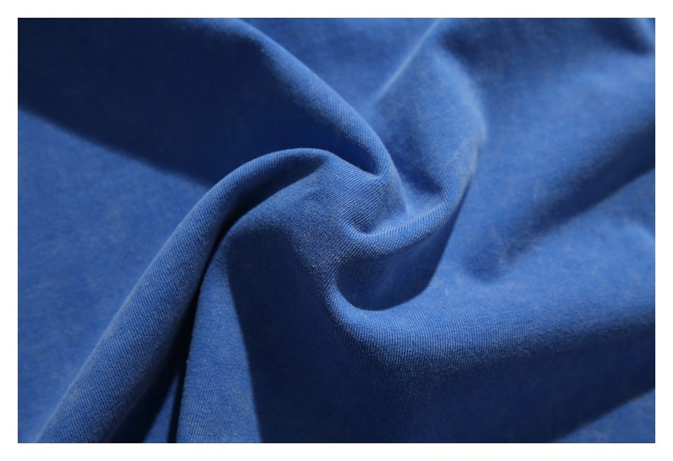 Close-up of plain blue fabric gathered into soft folds, showing its fine knit texture.