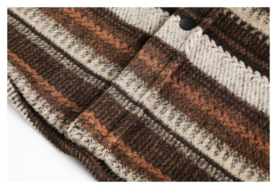 Close-up of a black snap button on the front of a brown, rust, and cream plaid garment.
