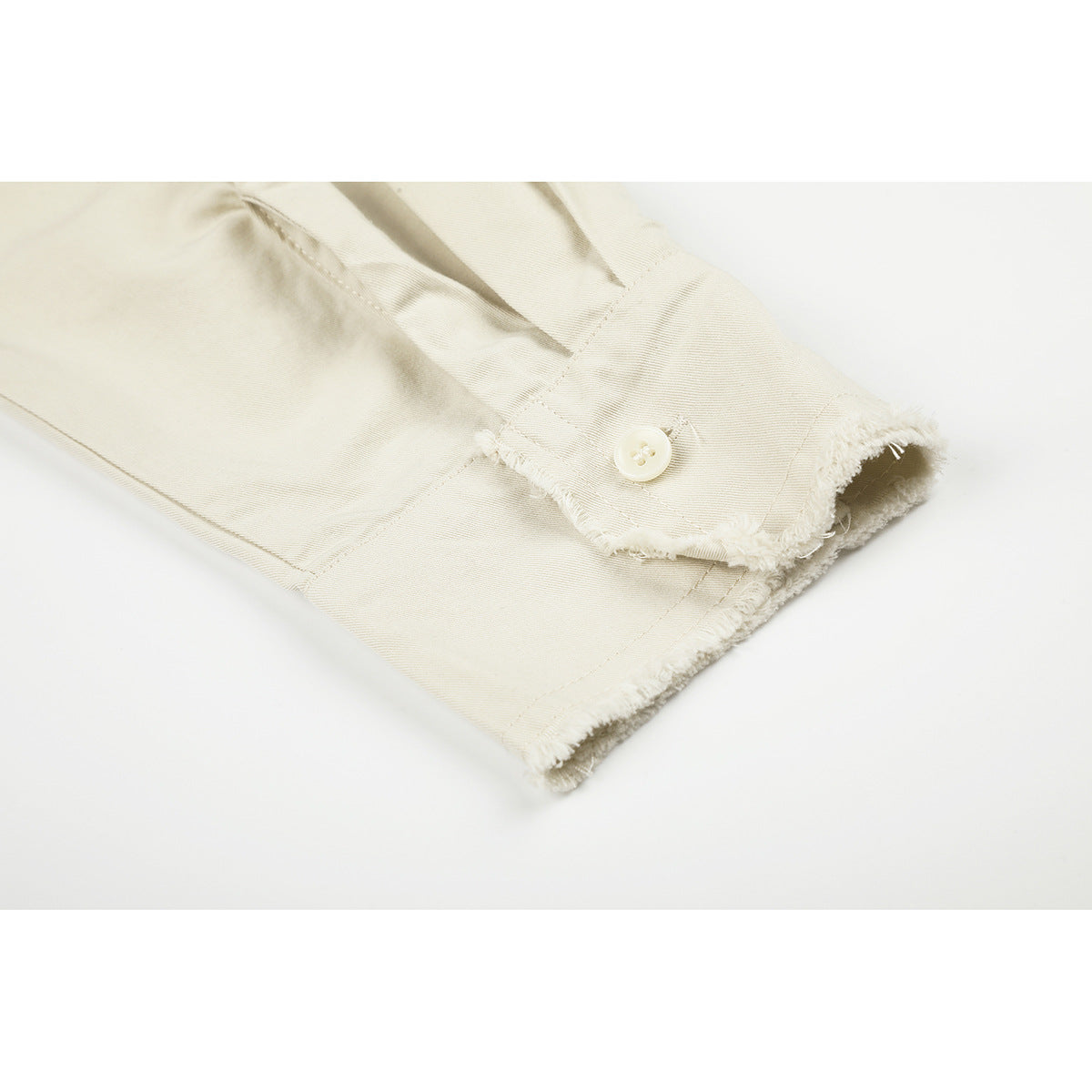 Close-up of an off-white shirt cuff with a button and frayed edges.
