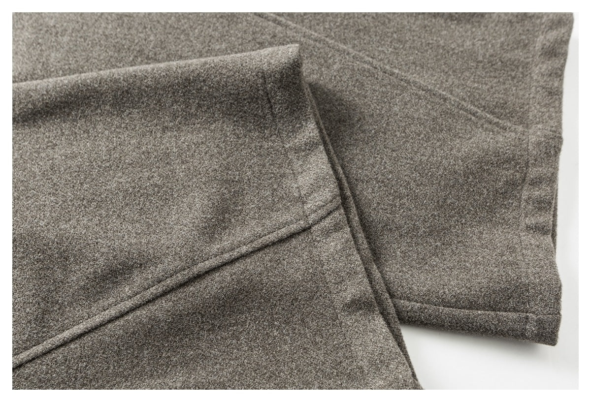 Close-up of gray-brown garment fabric showing a stitched hem and overlapping seam.