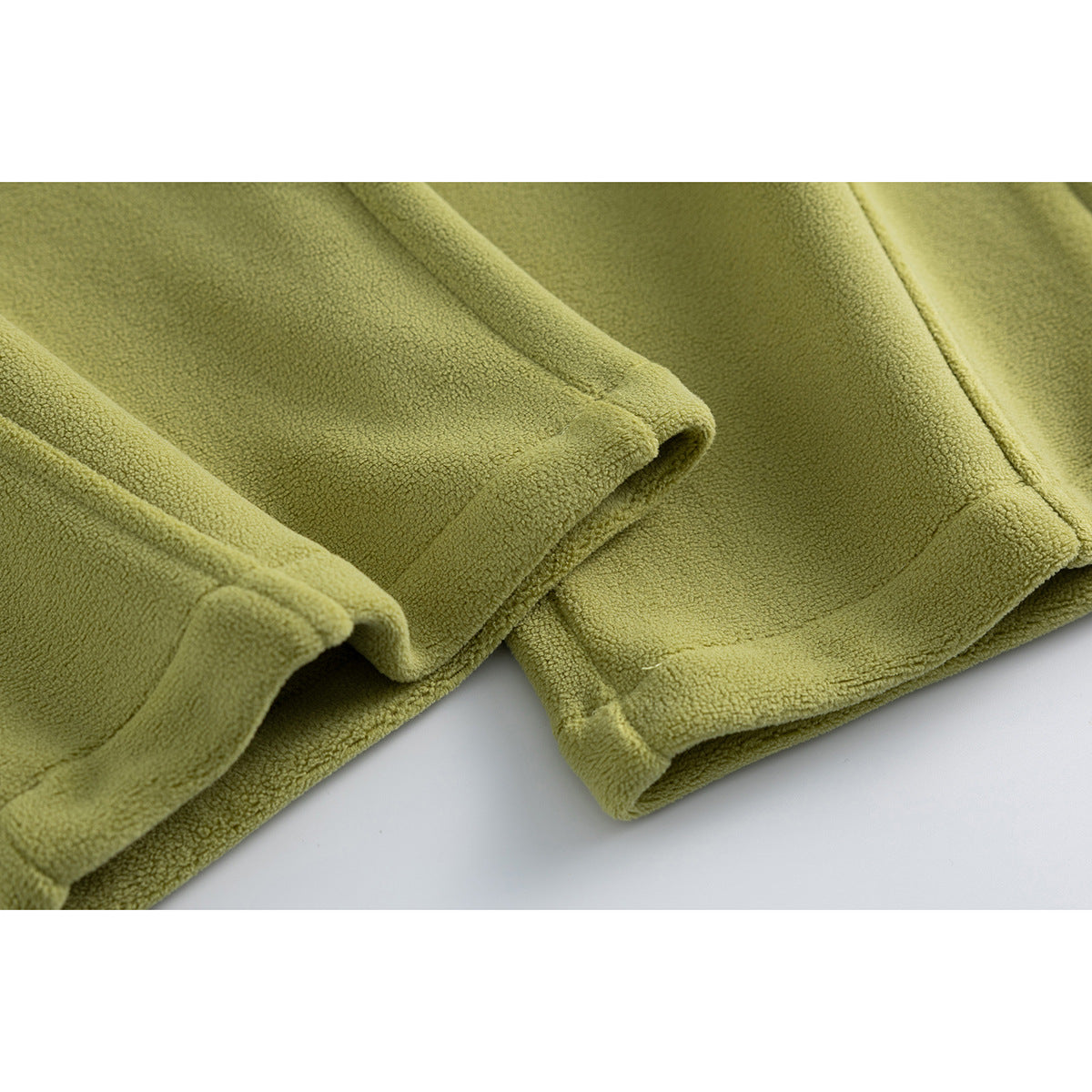 Close-up of olive green pants showing stitched leg hems and the textured fabric.
