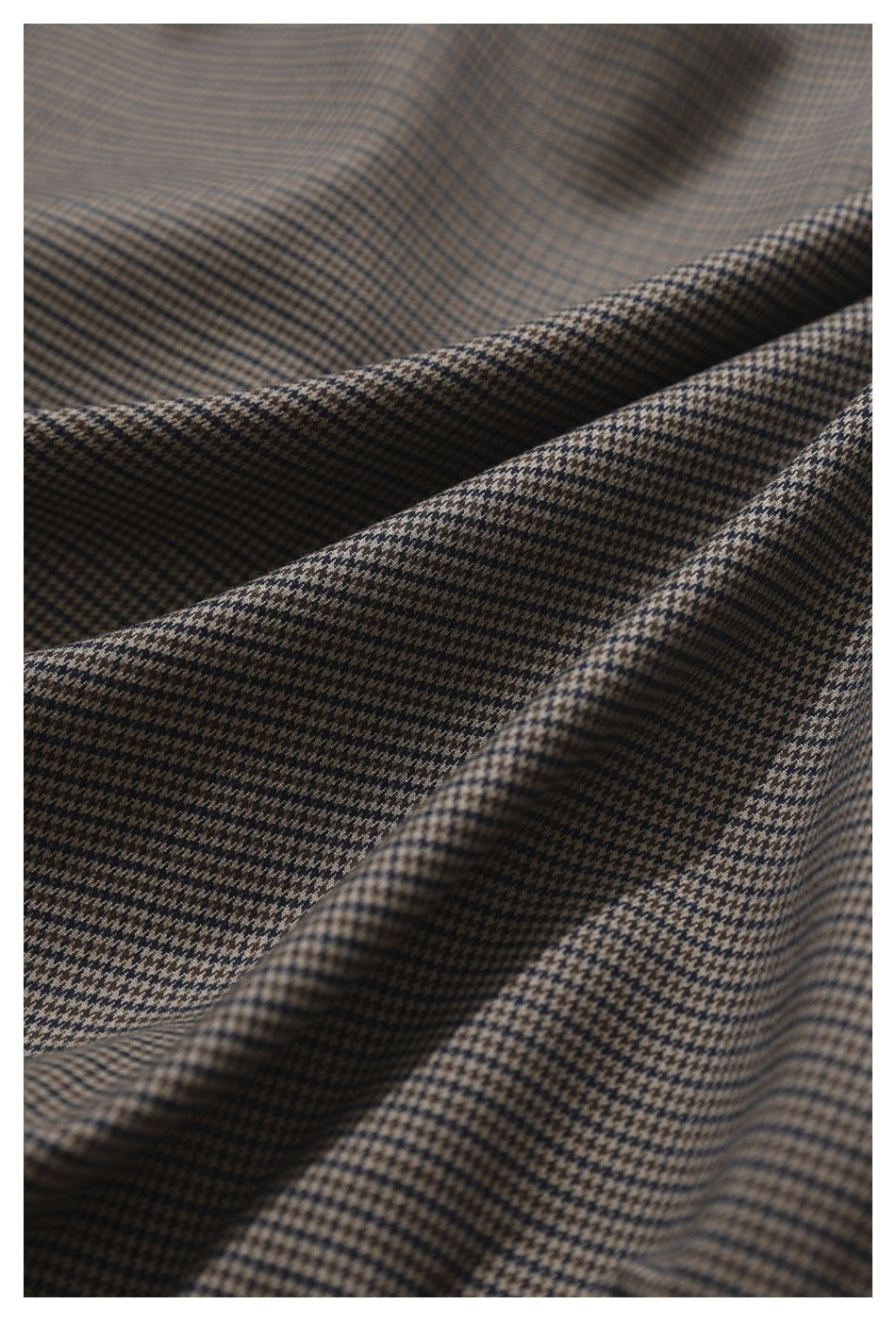 Close-up of brown and black houndstooth fabric arranged in soft folds.