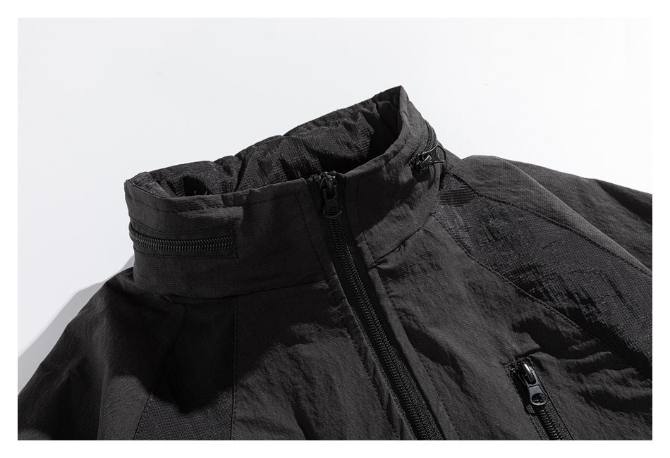 Close-up of the dark jacket's high collar and front zipper, with small zip pockets near the collar and chest.