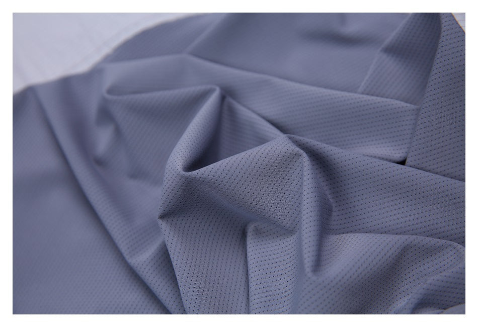 Close-up of draped blue-gray fabric with a fine perforated texture.