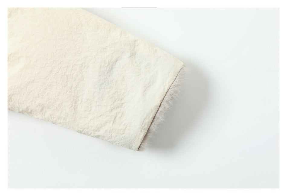 Close-up of a cream sleeve cuff with a narrow strip of fuzzy lining at the edge.