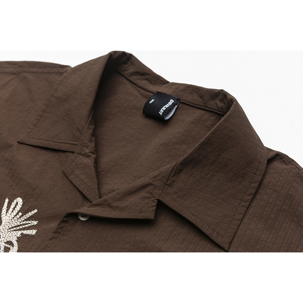 Close-up of a dark brown shirt's pointed collar, stitching, and black neck label.
