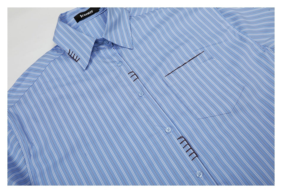 Light blue button-up shirt with thin white and dark stripes, pointed collar, chest pocket, and dark decorative stitching.