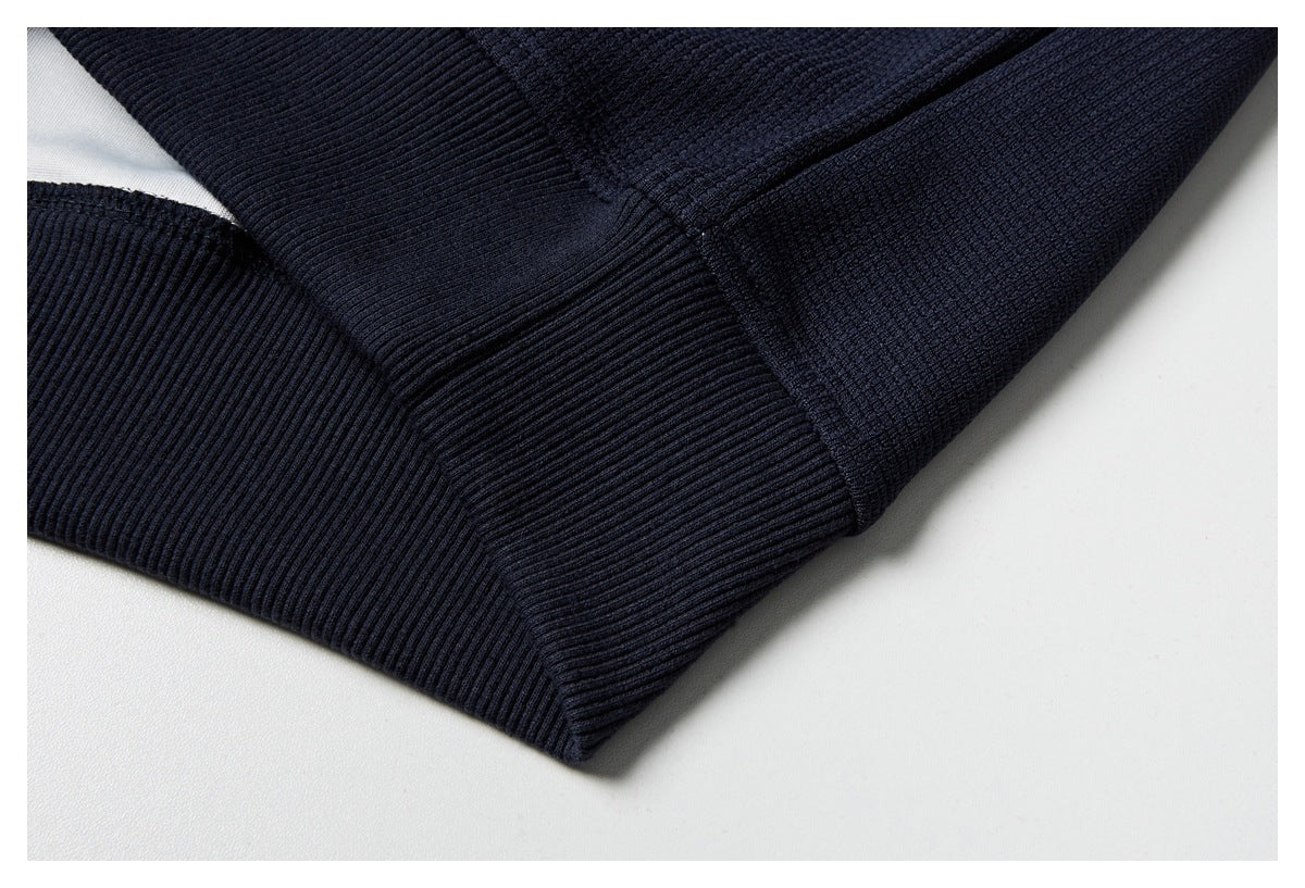 Close-up of a dark navy garment hem with a wide ribbed band and textured stitching.