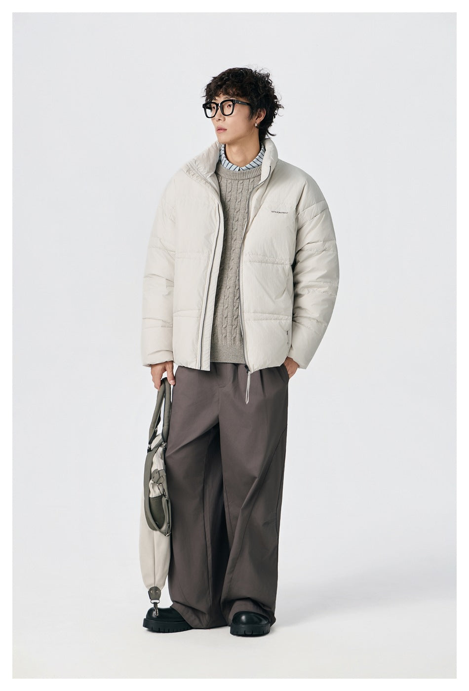Model wearing an ivory zip-front puffer jacket with a high collar, styled with dark loose trousers.
