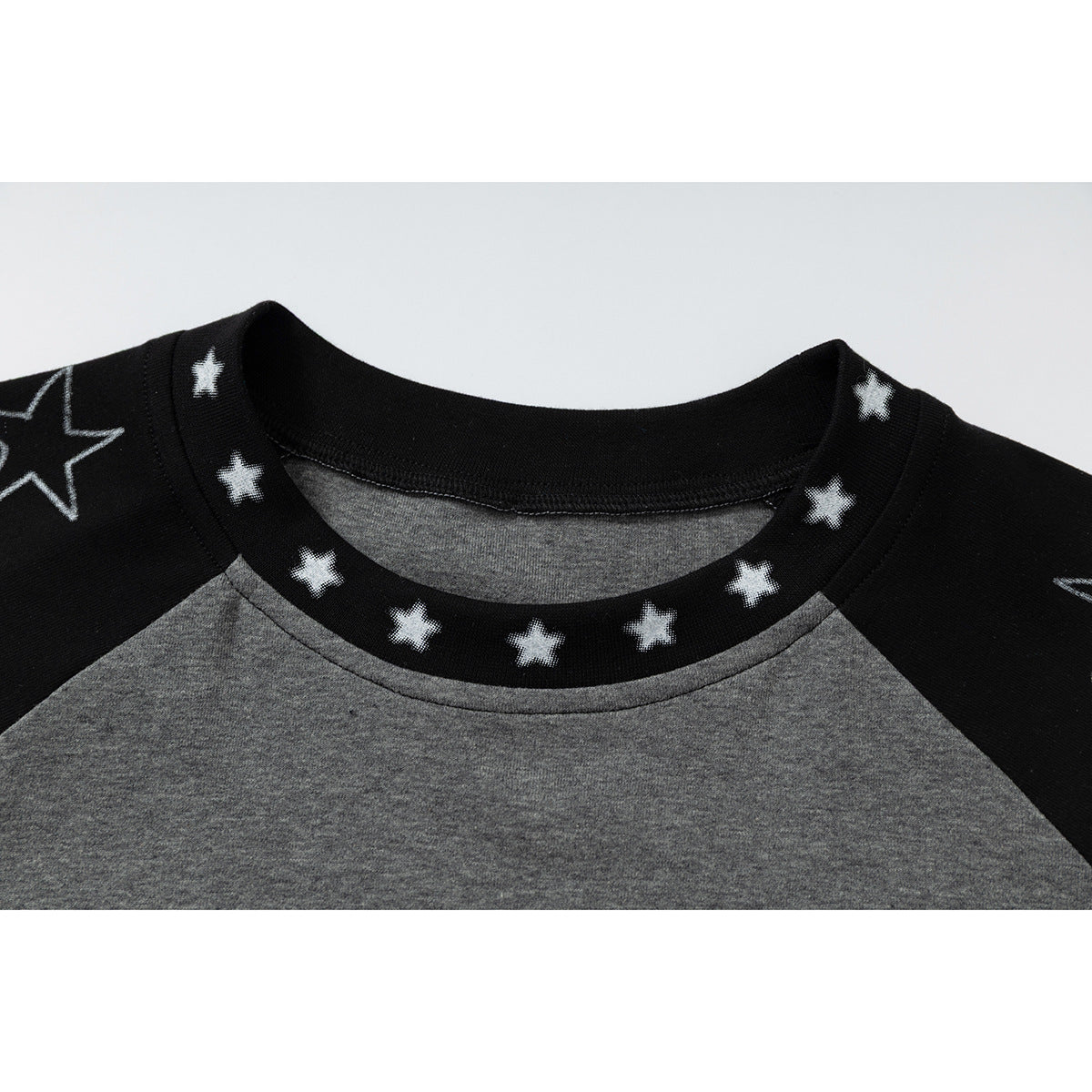 Close-up of a gray raglan T-shirt with black, white-star-print shoulders and a star-patterned crew neck.