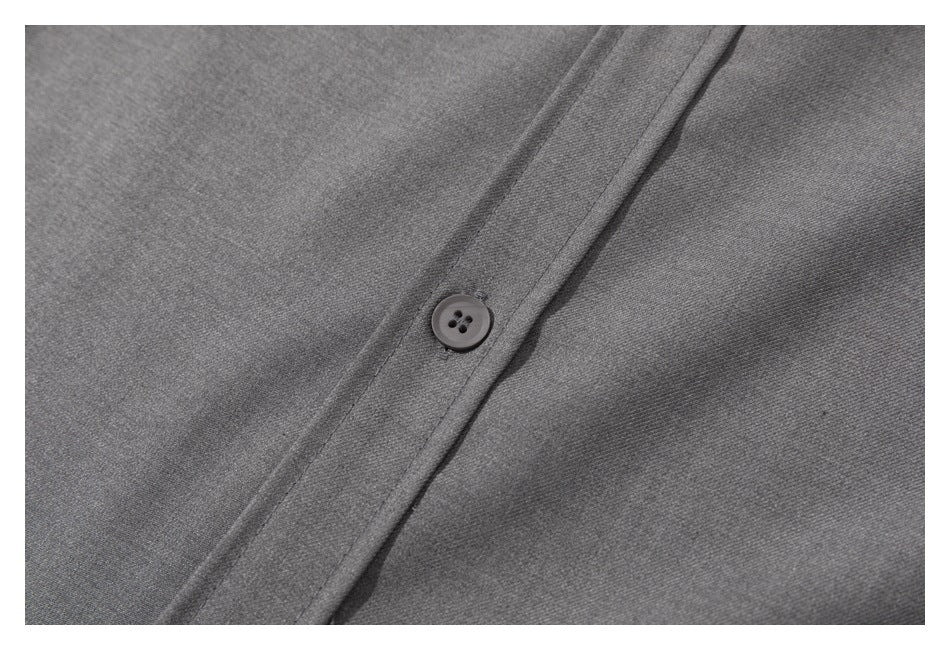 Close-up of a gray shirt button and the surrounding fabric and placket stitching.
