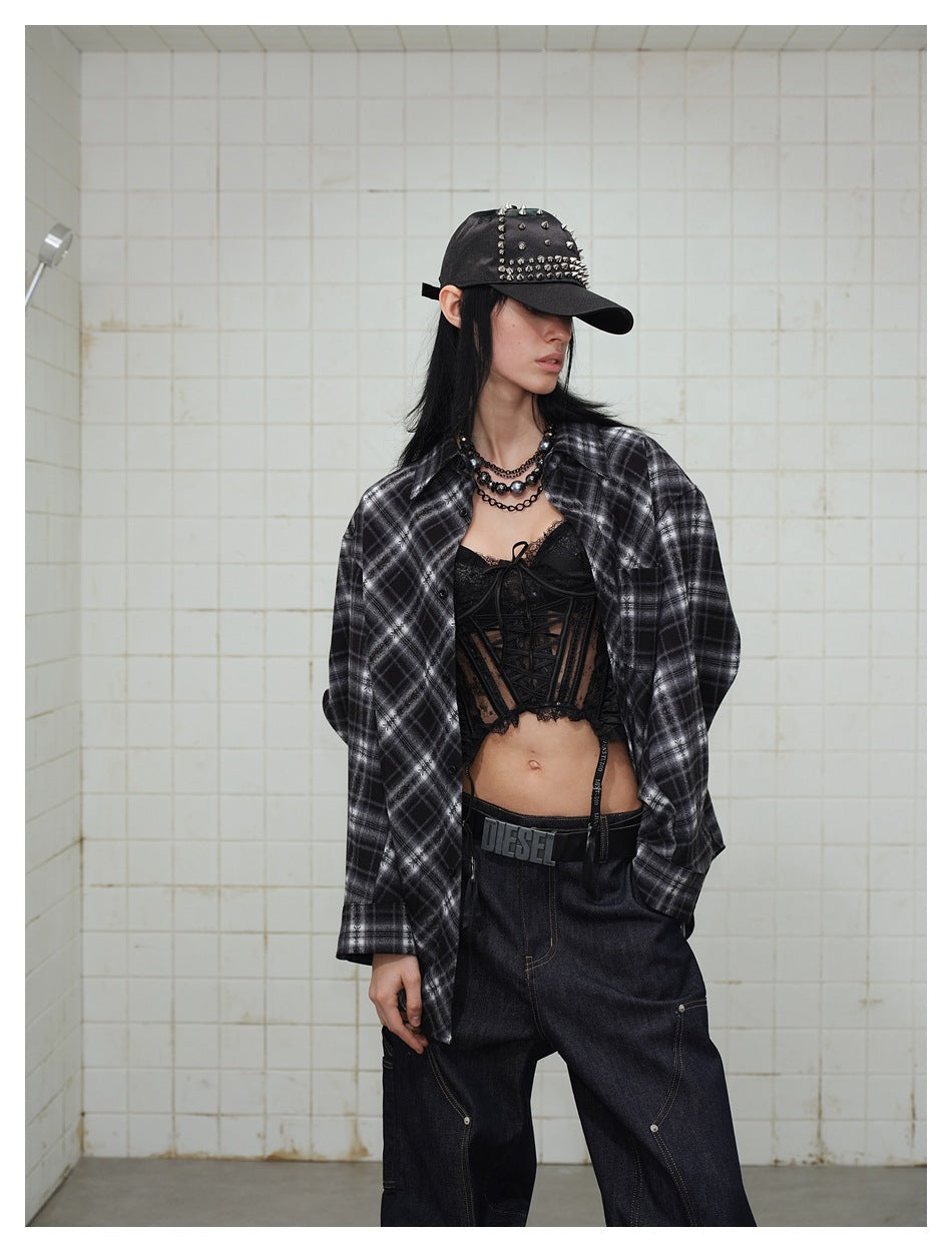 Model wearing an open black and gray plaid shirt over a black lace-up top.