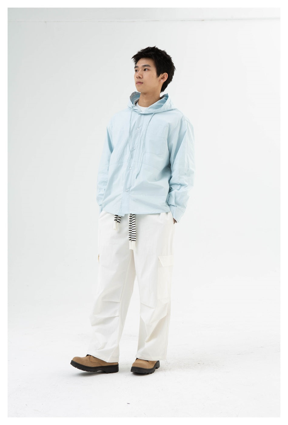 Full-length model wearing a pale blue hooded button-front shirt and white cargo pants.