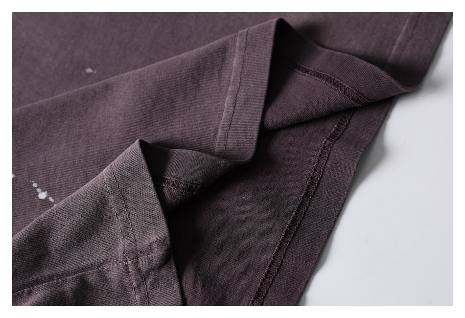 Close-up of the dark plum shirt's folded hem and interior seam stitching, with white spots visible nearby.