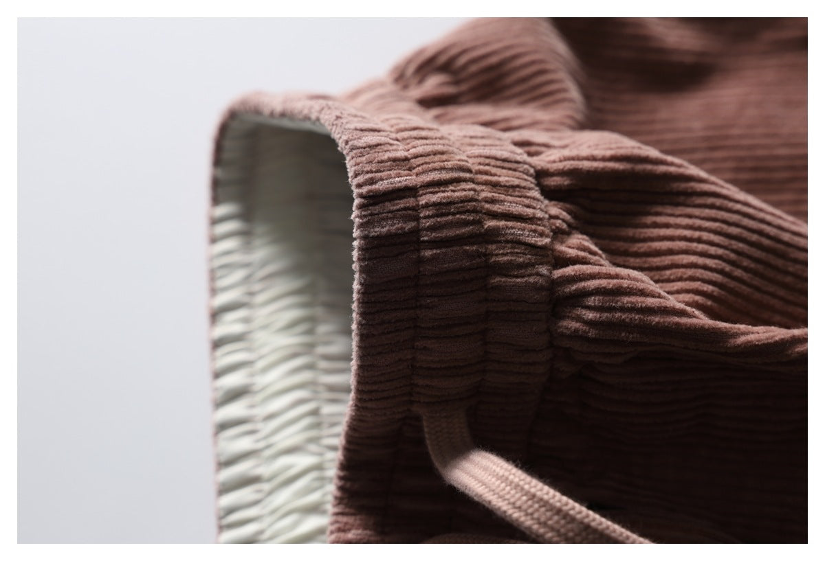 Close-up of the gathered waistband and inside finish of dusty mauve-brown ribbed trousers.