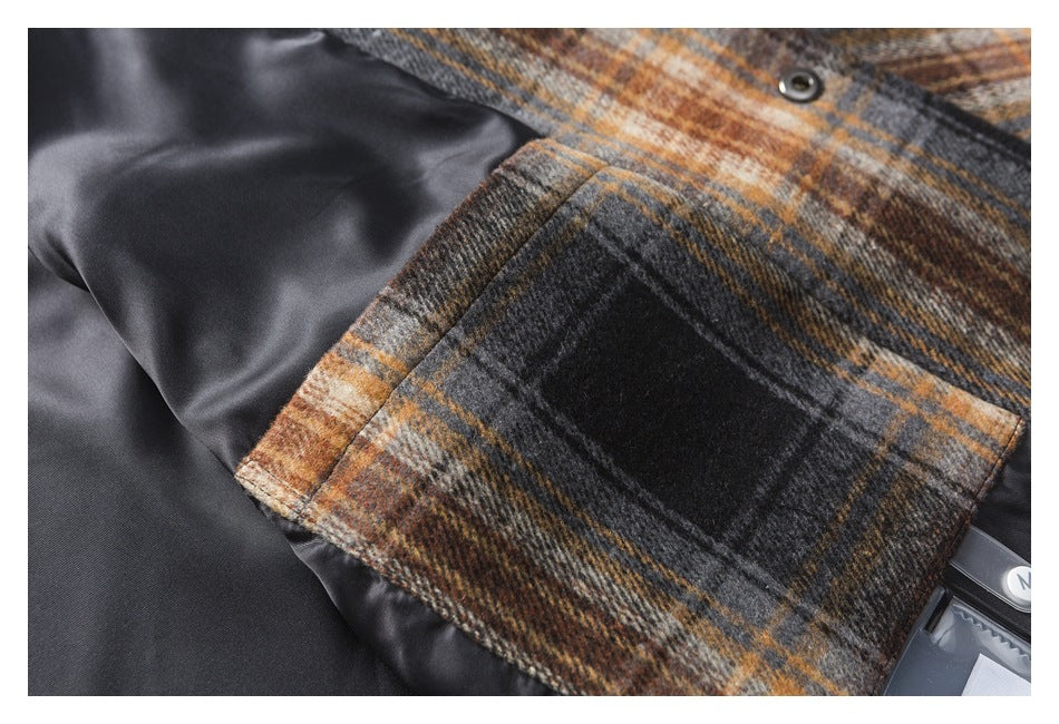 Close-up of a brown, gray, and black plaid garment pocket with a dark lining and metal snap.