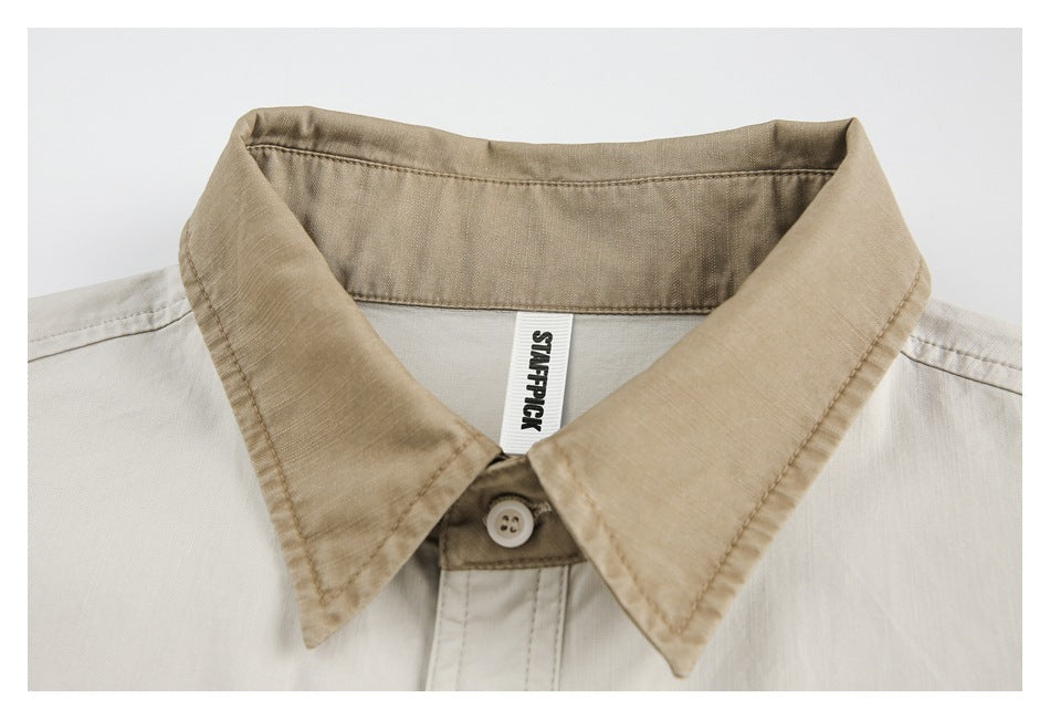 Close-up of an off-white shirt with a tan collar, button, and sewn-in neck label.