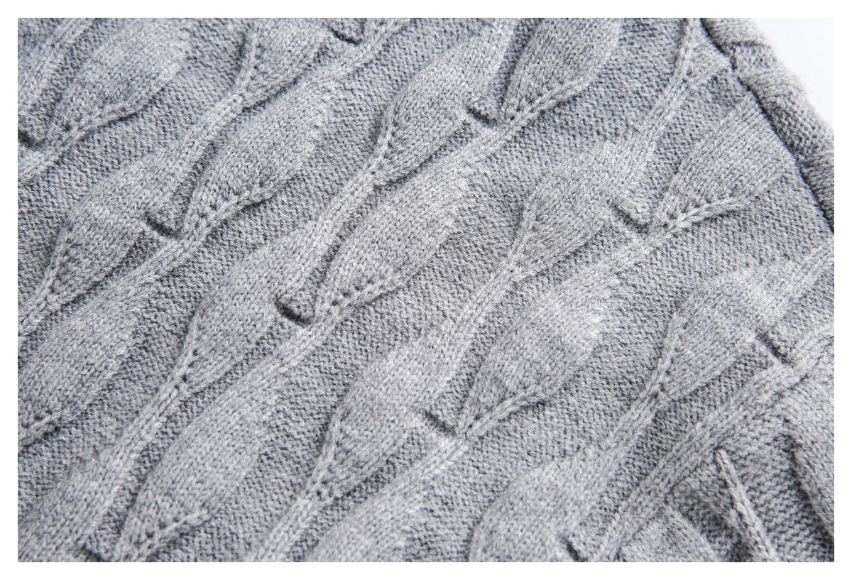 Close-up of the gray sweater's raised cable-knit pattern and textured stitches.